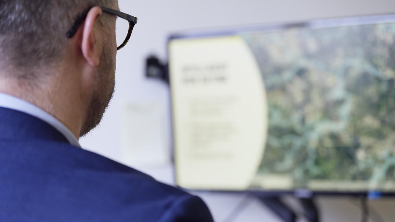 Over the shoulder of professor looking at a flood map on their computer screen