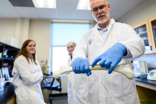 Dr. Thomas Willett pointing to a section of a femur bone