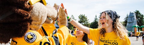 Student in gold shirt greets Waterloo's mascot