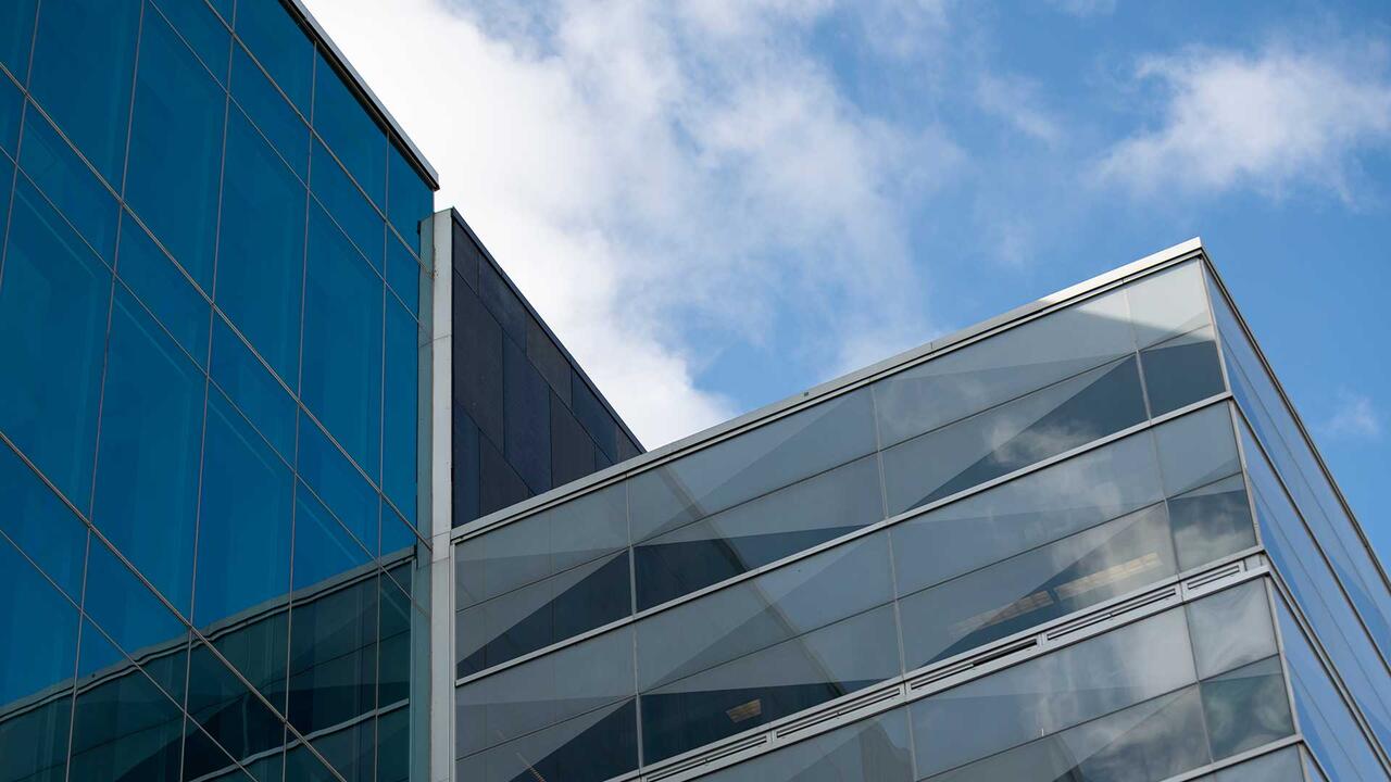 Mirrored windows of building reflect a partially cloudy sky