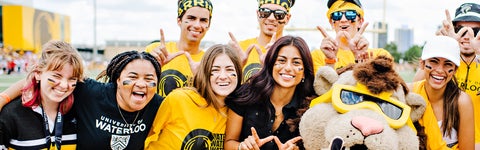 Students in black and gold smile at the camera