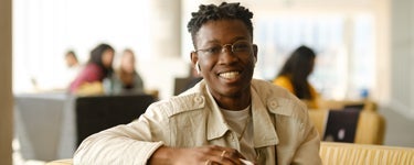 Student wearing beige jacket looking directly into the camera