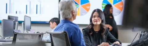 Two people talking with large pie charts in the background