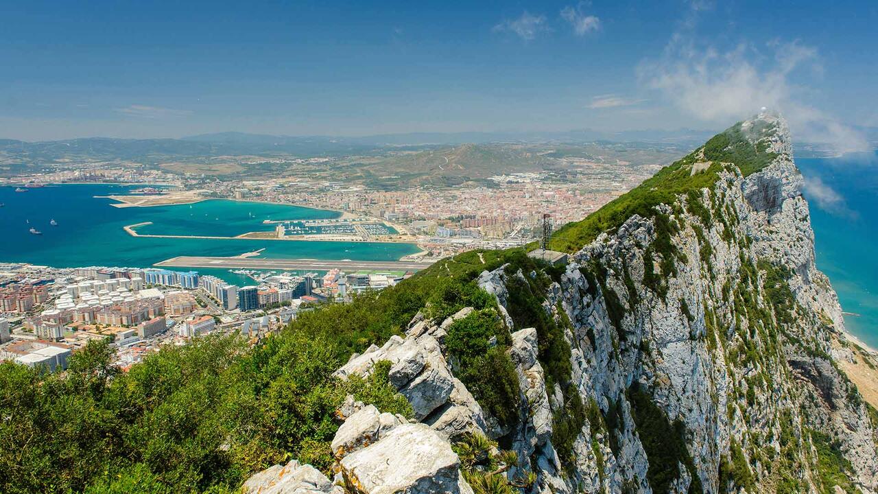 A cliff top in Gibraltar, overlooking bright blue ocean and cities
