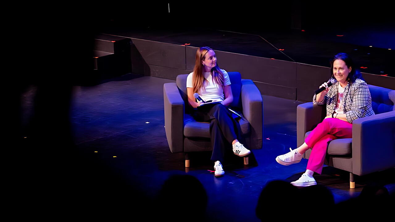 Rachel Bartholomew is interviewed on stage, seated with an interviewer under theatre lights