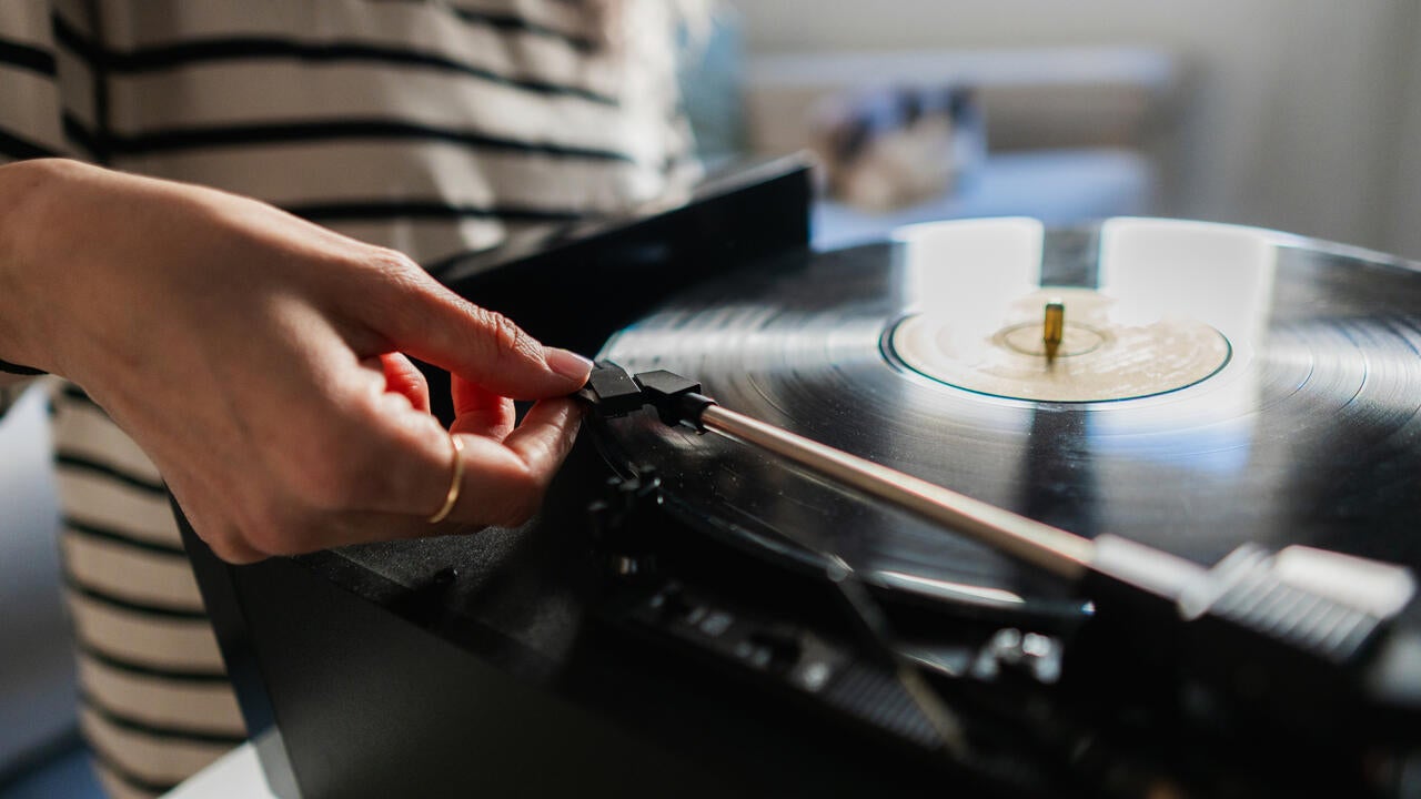 Woman places record-player needle on a record