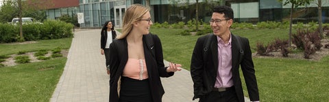 Two students in interview suits walk along a path at the University of Waterloo