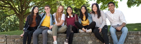 Group of students sitting on short stone wall at the University of Waterloo