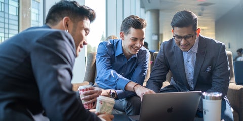 Students in dress shirts look and point at a laptop