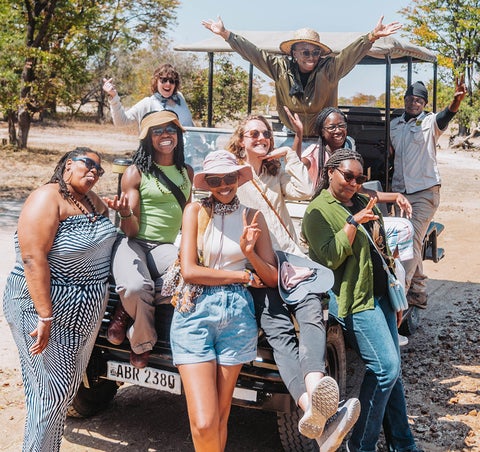 Group of people sitting on and around a safari vehicle