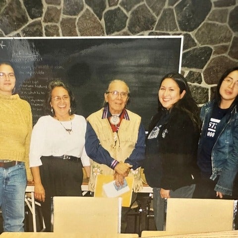 five people standing together smiling