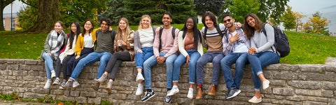 A group of students sitting on a low stone wall at the University of Waterloo