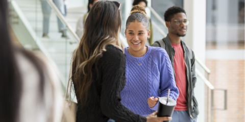 Two students talking inside building
