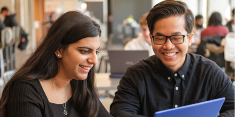 Two students working together on a laptop